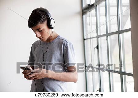 Stock Photo - Teenage boy texting by glass window. Fotosearch