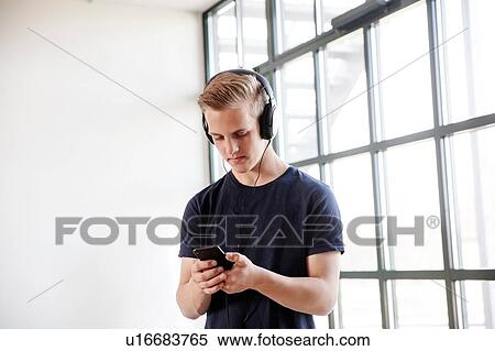 Stock Photography - Teenage boy texting by glass window. Fotosearch