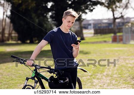 Picture - Teenage boy texting on pushbike. Fotosearch