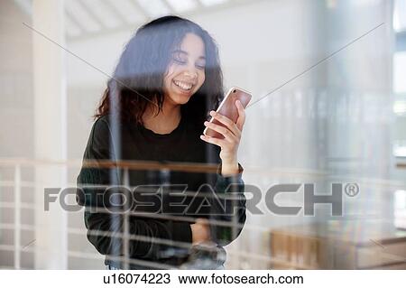 Teenage girl reading text message on cellphone by glass wall View Large Photo Image Stock Image - Teenage girl reading text message on cellphone by glass wall. Fotosearch