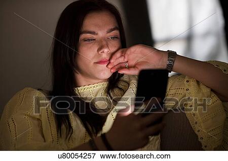 Teenage girl sitting on sofa in dark reading text message View Large Photo Image Stock Photo - Teenage girl sitting on sofa in dark reading text message. Fotosearch