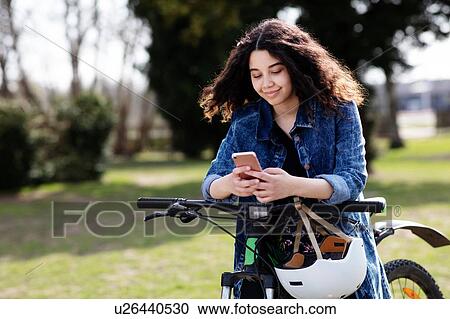 Teenage girl texting on pushbike View Large Photo Image Stock Image - Teenage girl texting on pushbike. Fotosearch