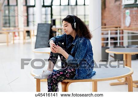 Stock Image - Teenage girl using headphones in school. Fotosearch