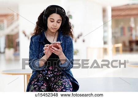 Stock Photo - Teenage girl using headphones in school. Fotosearch