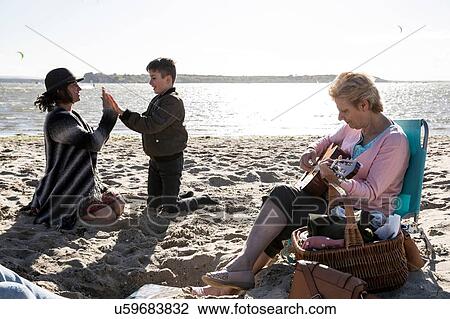 Stock Image - Three generation family enjoying beach. Fotosearch