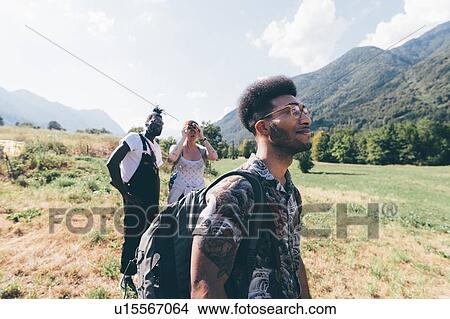Picture - Three young hiking friends looking up from field landscape, Primaluna, Trentino-Alto Adige, Italy. Fotosearch