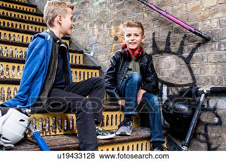 Twins talking on metal staircase View Large Photo Image Stock Photo - Twins talking on metal staircase. Fotosearch