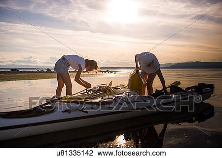 Stock Image - Two female kayakers preparing kayak, Quadra Island, Campbell River, Canada. Fotosearch