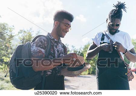 Stock Image - Two young male hikers preparing for hike on dirt track, Primaluna, Trentino-Alto Adige, Italy. Fotosearch