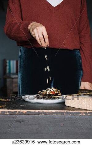 Woman sprinkling garnish on dinner plate, mid section View Large Photo Image Stock Photograph - Woman sprinkling garnish on dinner plate, mid section. Fotosearch