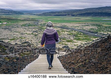 Stock Photo - Woman walking around Grabrok volcano, Iceland. Fotosearch