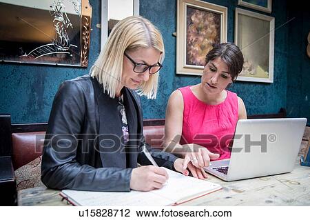 Stock Image - Women brainstorming business ideas in restaurant. Fotosearch