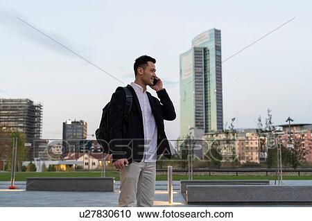 Young businessman in city making smartphone call, Milan, Italy View Large Photo Image Stock Image - Young businessman in city making smartphone call, Milan, Italy. Fotosearch