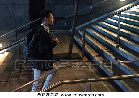 Young businessman moving up city stairway at night, Milan, Italy View Large Photo Image Stock Image - Young businessman moving up city stairway at night, Milan, Italy. Fotosearch