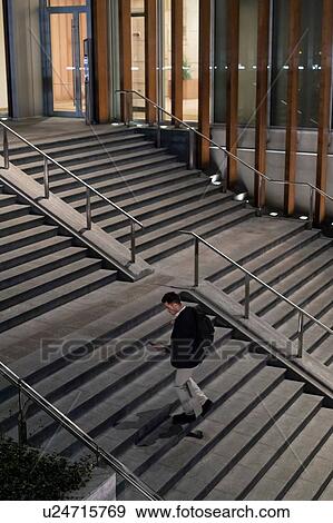 Young businessman moving up city stairway at night looking at smartphone, high angle view, Milan, Italy View Large Photo Image Stock Photo - Young businessman moving up city stairway at night looking at smartphone, high angle view, Milan, Italy. Fotosearch
