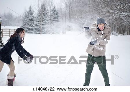 Stock Image - Young couple having snowball fight in snow covered forest, Ontario, Canada. Fotosearch