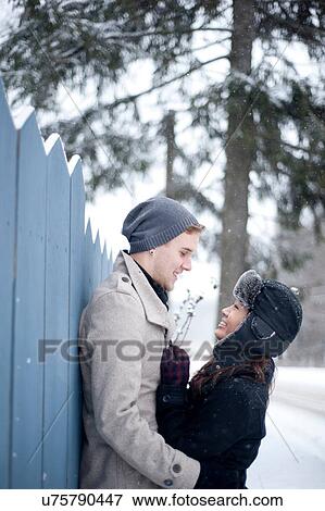 Young couple hugging against fence in snow View Large Photo Image Stock Photo - Young couple hugging against fence in snow. Fotosearch