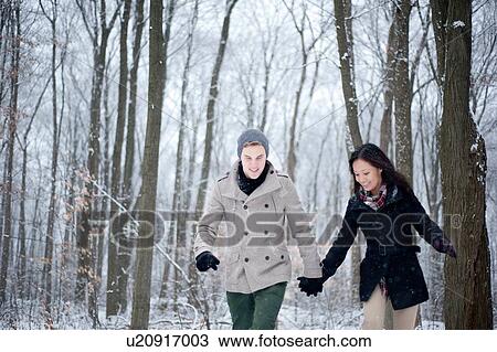 Young couple walking hand in hand in snow covered forest, Ontario, Canada View Large Photo Image Stock Image - Young couple walking hand in hand in snow covered forest, Ontario, Canada. Fotosearch