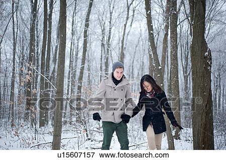 Stock Photo - Young couple walking hand in hand in snow covered forest, Ontario, Canada. Fotosearch