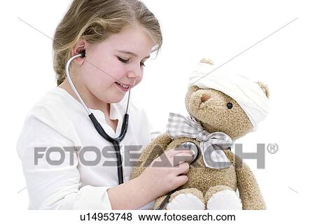 Stock Photo - Young girl playing with teddy bear and stethoscope.. Fotosearch