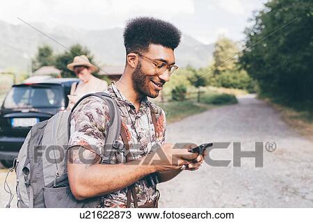 Young male hiker on dirt track looking at smartphone,, Primaluna, Trentino-Alto Adige, Italy View Large Photo Image Stock Image - Young male hiker on dirt track looking at smartphone,, Primaluna, Trentino-Alto Adige, Italy. Fotosearch