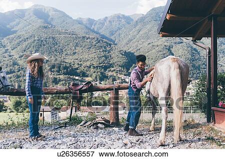 Stock Photo - Young man grooming horse in rural equestrian arena, Primaluna, Trentino-Alto Adige, Italy. Fotosearch