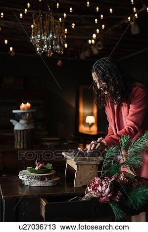 Stock Image - Young woman at rustic table preparing food. Fotosearch