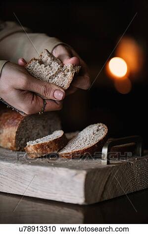 Young woman breaking brown bread on rustic chopping board, close up of hands View Large Photo Image Stock Image - Young woman breaking brown bread on rustic chopping board, close up of hands. Fotosearch
