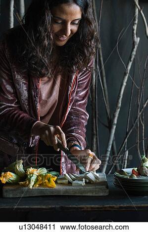 Young woman chopping fresh food on rustic cutting board View Large Photo Image Stock Image - Young woman chopping fresh food on rustic cutting board. Fotosearch