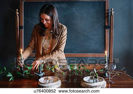 Young woman decorating vintage dinner table with candle and foliage View Large Photo Image Stock Image - Young woman decorating vintage dinner table with candle and foliage. Fotosearch