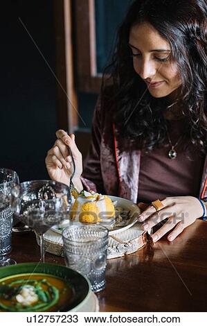 Young woman eating dessert at restaurant table View Large Photo Image Stock Image - Young woman eating dessert at restaurant table. Fotosearch