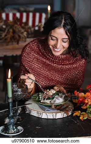 Stock Image - Young woman eating fresh salad at vintage table. Fotosearch