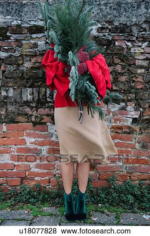 Stock Photo - Young woman in front of old brick wall holding christmas tree. Fotosearch