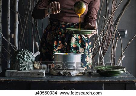 Young woman ladling fresh soup from saucepan at rustic kitchen counter, mid section View Large Photo Image Picture - Young woman ladling fresh soup from saucepan at rustic kitchen counter, mid section. Fotosearch