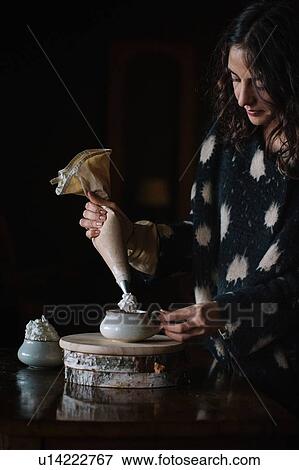 Young woman piping cream into bowl using piping bag View Large Photo Image Stock Photo - Young woman piping cream into bowl using piping bag. Fotosearch