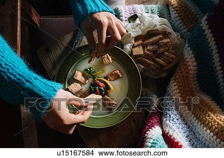 Young woman placing savoury biscuits in bowl of fresh food View Large Photo Image Picture - Young woman placing savoury biscuits in bowl of fresh food. Fotosearch