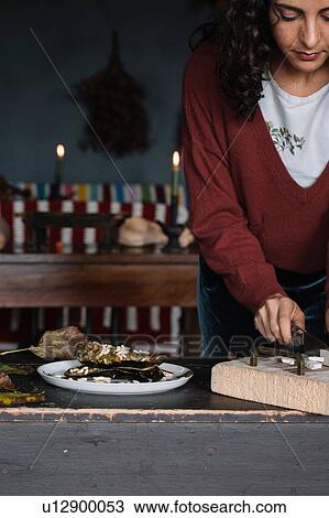 Stock Image - Young woman slicing food on chopping board, cropped. Fotosearch