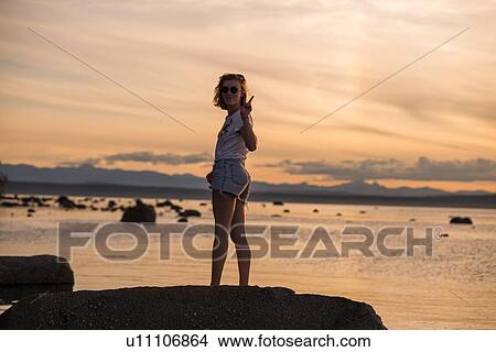 Young woman standing on rock at sunset, portrait, Quadra Island, Campbell River, Canada View Large Photo Image Picture - Young woman standing on rock at sunset, portrait, Quadra Island, Campbell River, Canada. Fotosearch