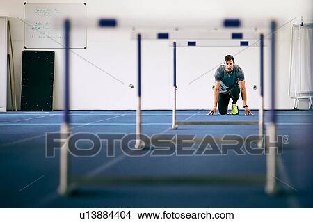 Athlete getting ready for hurdles on indoor running track View Large Photo Image Picture - Athlete getting ready for hurdles on indoor running track. Fotosearch