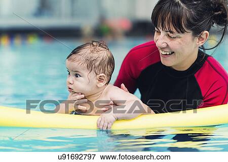 Stock Photo - Baby with instructor in swimming pool. Fotosearch