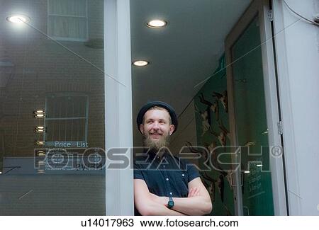 Stock Image - Barber at entrance of barbershop. Fotosearch