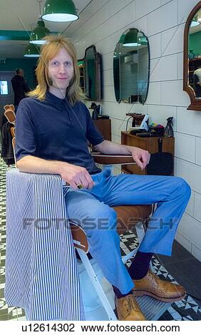 Stock Image - Barber relaxing in barbershop. Fotosearch