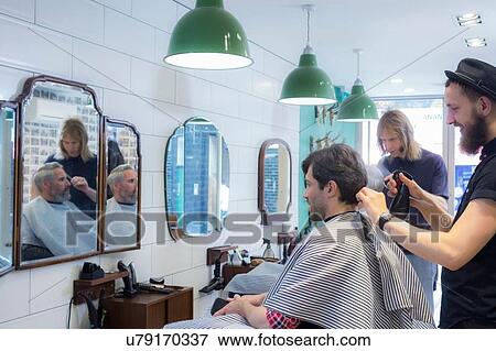 Stock Photo - Barbers working in barbershop. Fotosearch