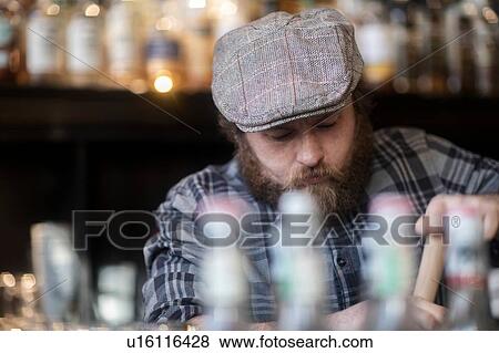 Barman working behind bar in traditional Irish public house View Large Photo Image Stock Photo - Barman working behind bar in traditional Irish public house. Fotosearch