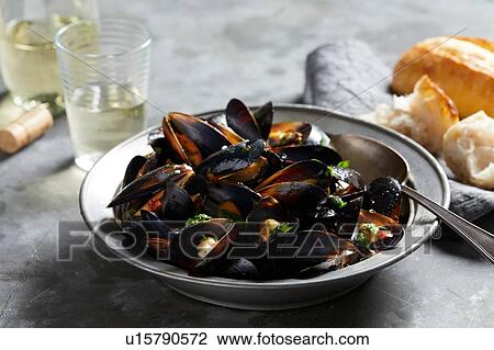 Stock Image - Bowl of garlic mussels with glass of white wine. Fotosearch