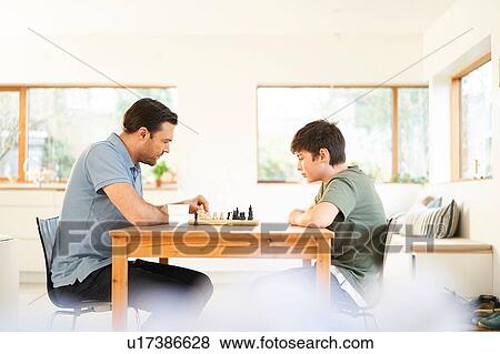Boy and father playing chess at living room table View Large Photo Image Stock Photo - Boy and father playing chess at living room table. Fotosearch