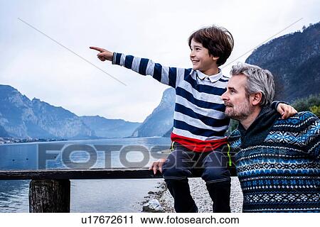 Boy and father pointing from lakeside pier, Lake Como, Onno, Lombardy, Italy View Large Photo Image Stock Image - Boy and father pointing from lakeside pier, Lake Como, Onno, Lombardy, Italy. Fotosearch
