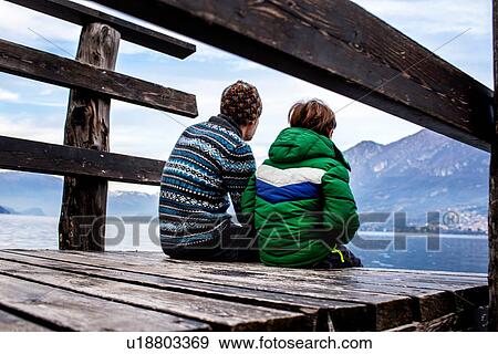 Boy and father sitting on lakeside pier, rear view, Lake Como, Onno, Lombardy, Italy View Large Photo Image Stock Photo - Boy and father sitting on lakeside pier, rear view, Lake Como, Onno, Lombardy, Italy. Fotosearch