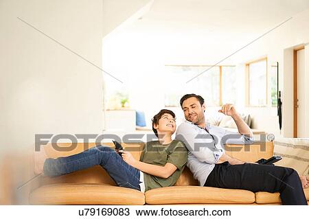 Boy and father using digital tablets back to back on sofa View Large Photo Image Stock Image - Boy and father using digital tablets back to back on sofa. Fotosearch