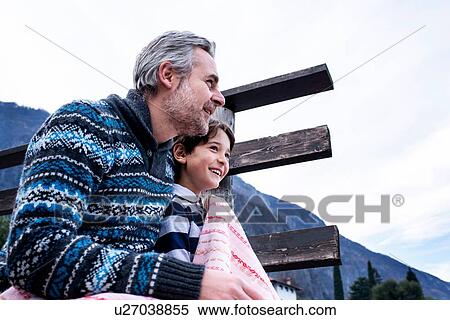 Stock Photography - Boy and father with blanket on lakeside pier, Lake Como, Onno, Lombardy, Italy. Fotosearch